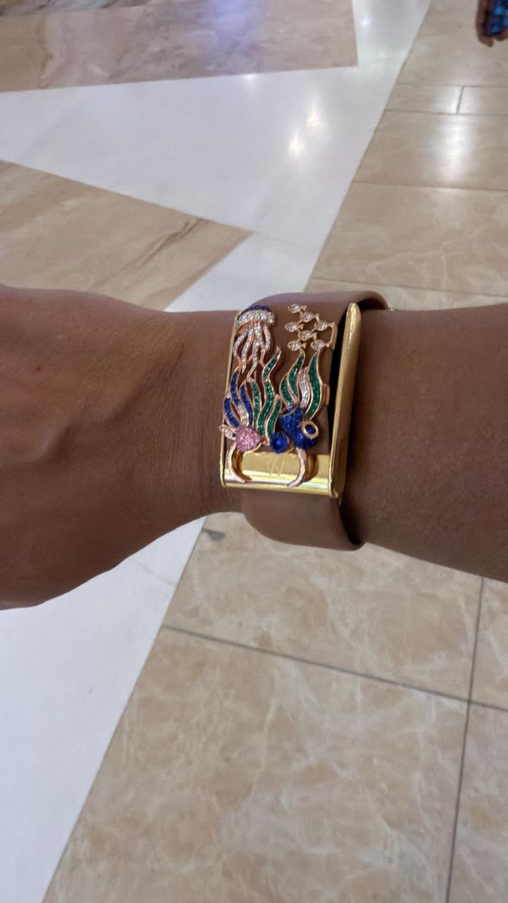 Colorful gold-tone WHOOP accessory on a brown band